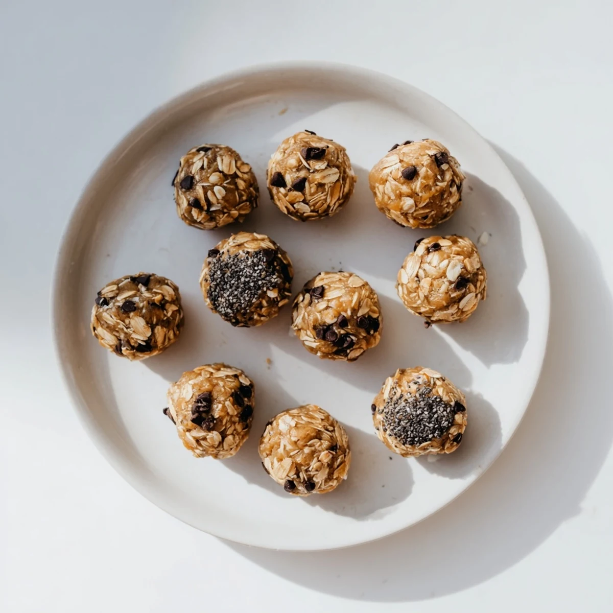 Homemade peanut butter energy balls rolled with oats and dark chocolate chips on a white plate