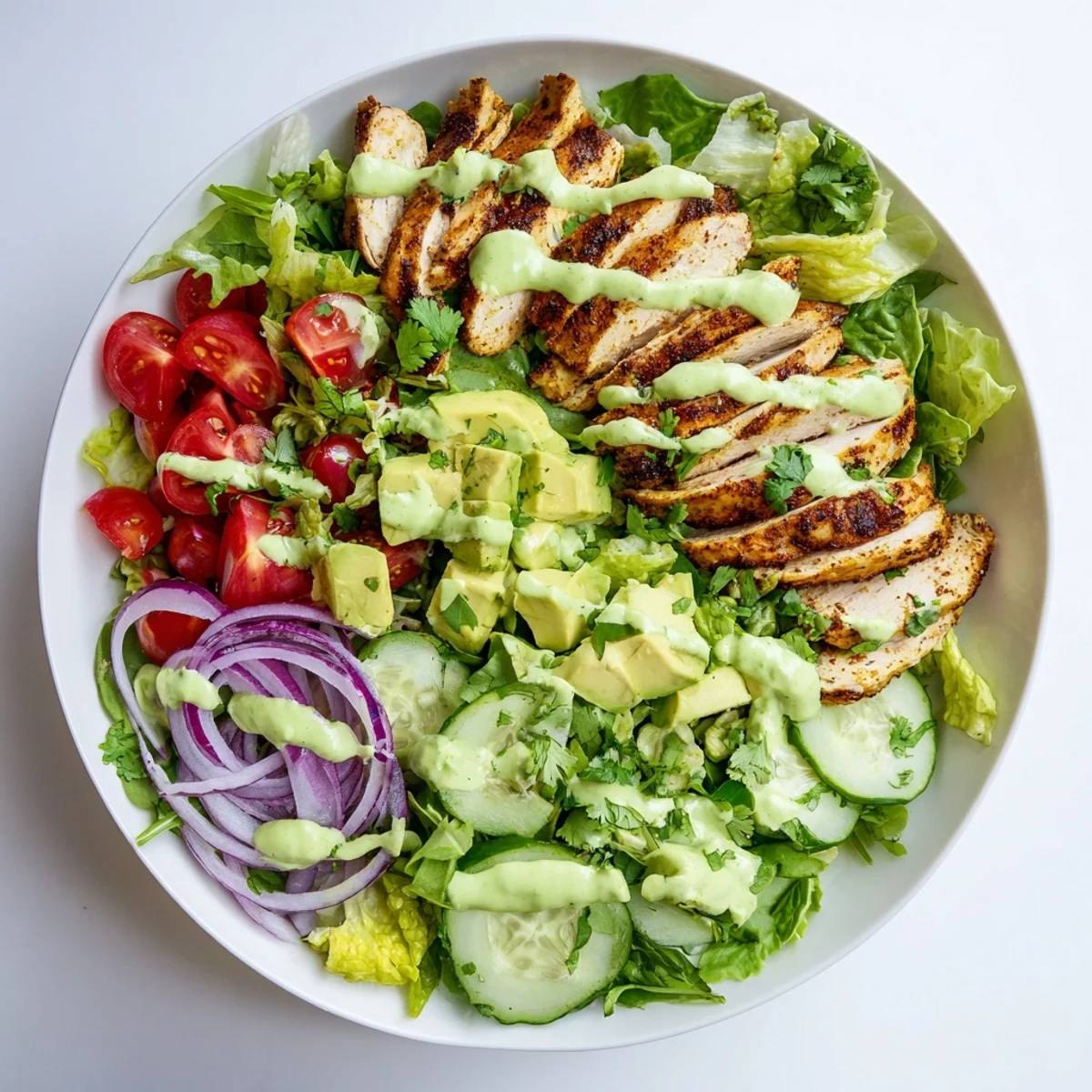 Vibrant salad bowl featuring tender grilled chicken strips, ripe avocado chunks, cherry tomatoes, and cucumber with creamy avocado lime dressing