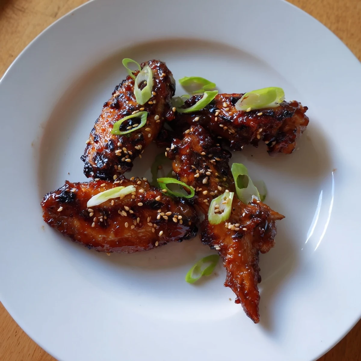 Sticky Teriyaki Baked Wings glistening with sesame, garnished with sliced spring onions
