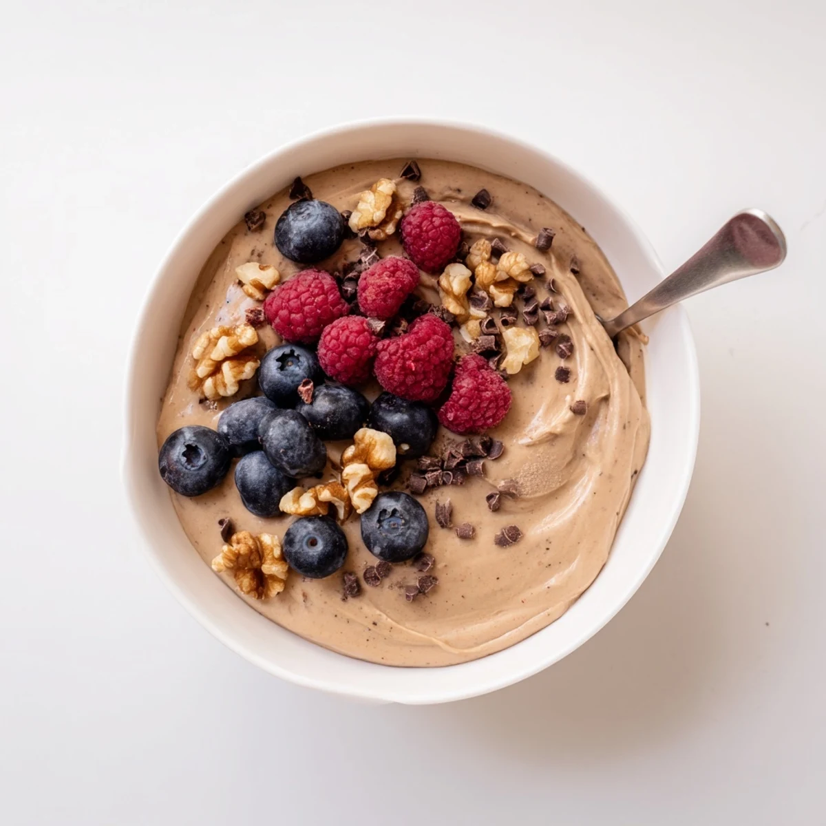 Creamy banana nice cream served in a bowl topped with fresh berries and nuts