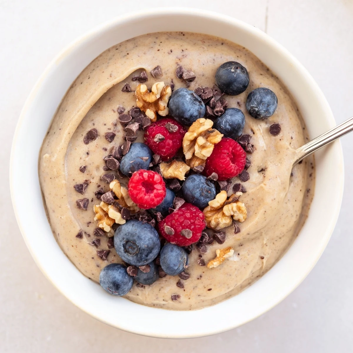 Healthy banana nice cream recipe swirled with dark chocolate chips in a white bowl