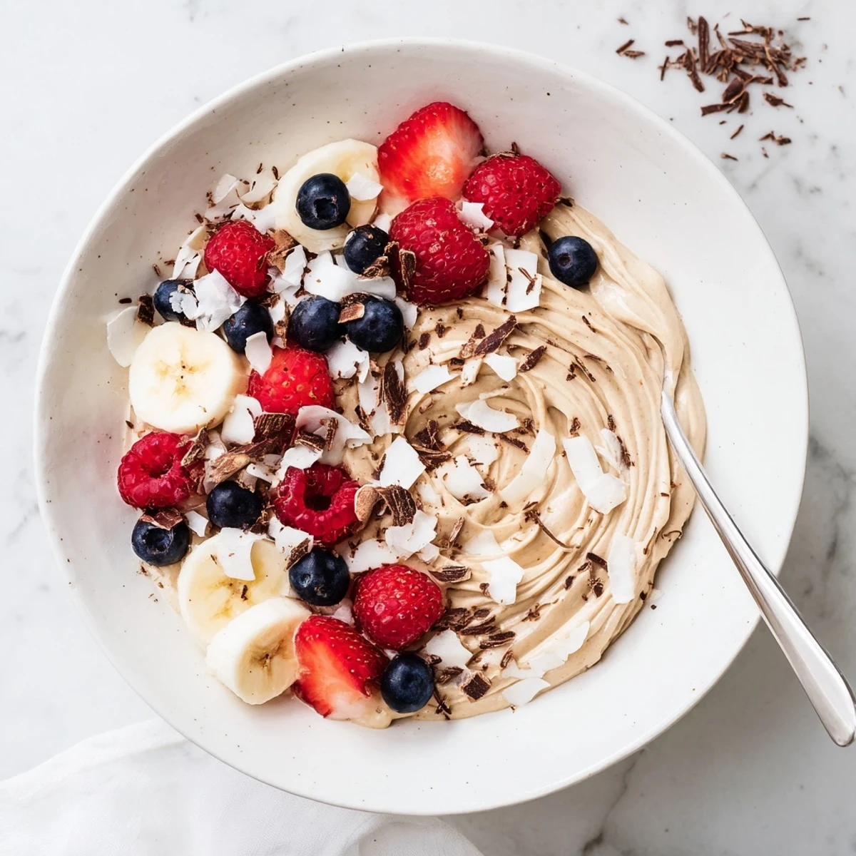 Creamy healthy nice cream recipe served in a bowl with fresh banana slices and dark chocolate shavings