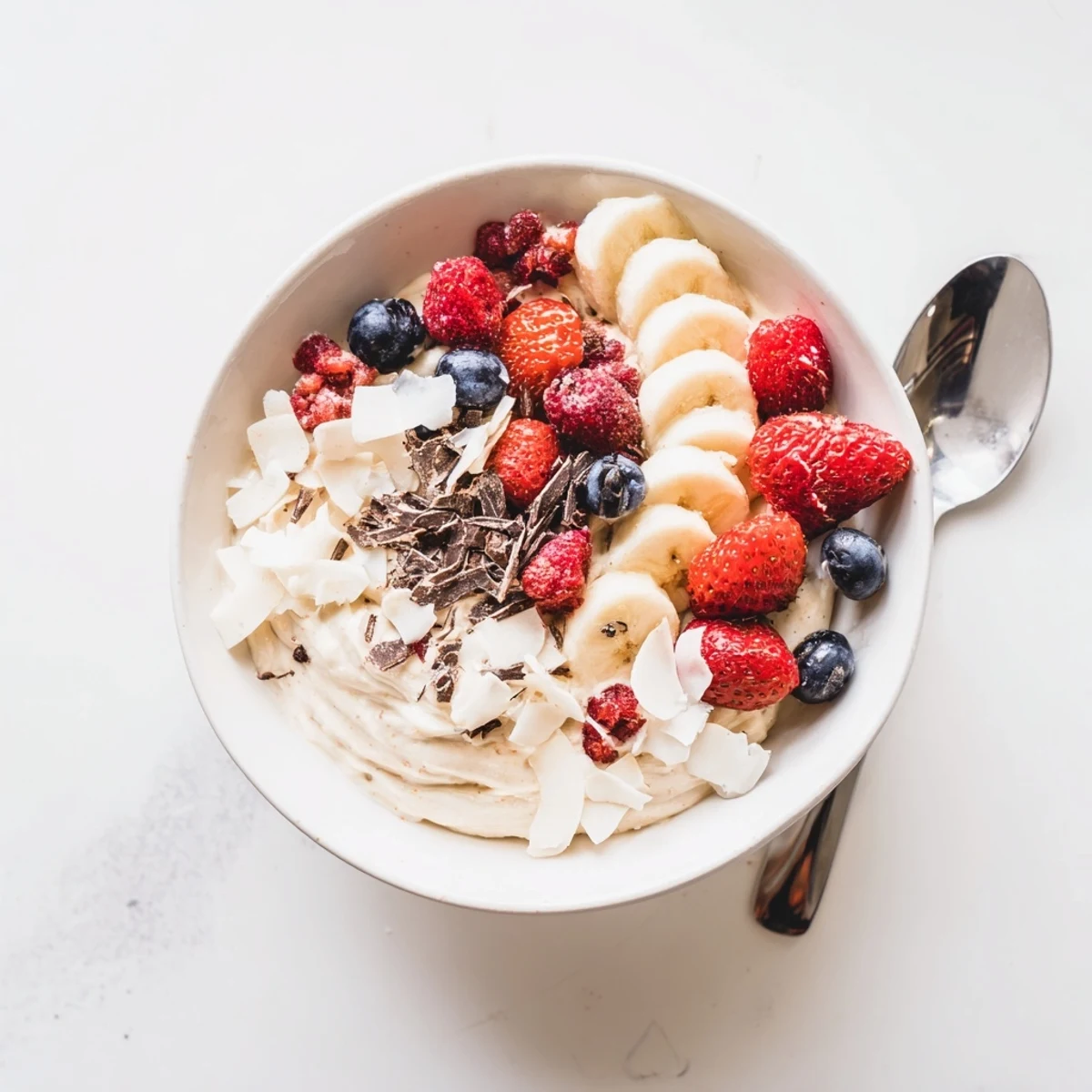 Vegan healthy nice cream recipe topped with colorful mixed berries and coconut flakes for a refreshing dairy-free dessert