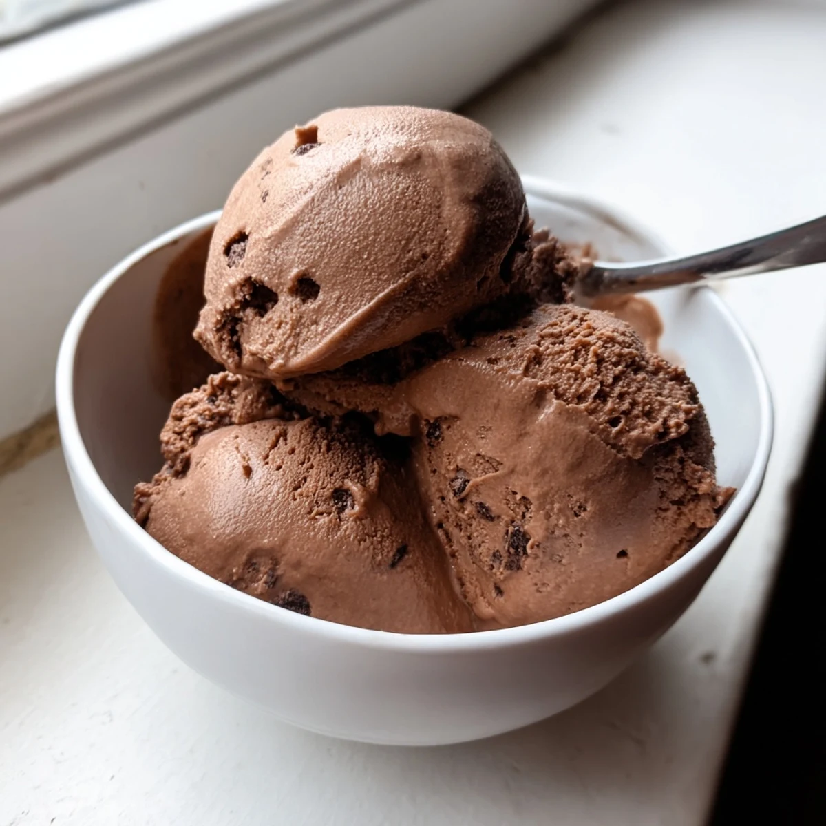 Creamy chocolate sourdough ice cream scooped into a bowl with dark chocolate shavings on top