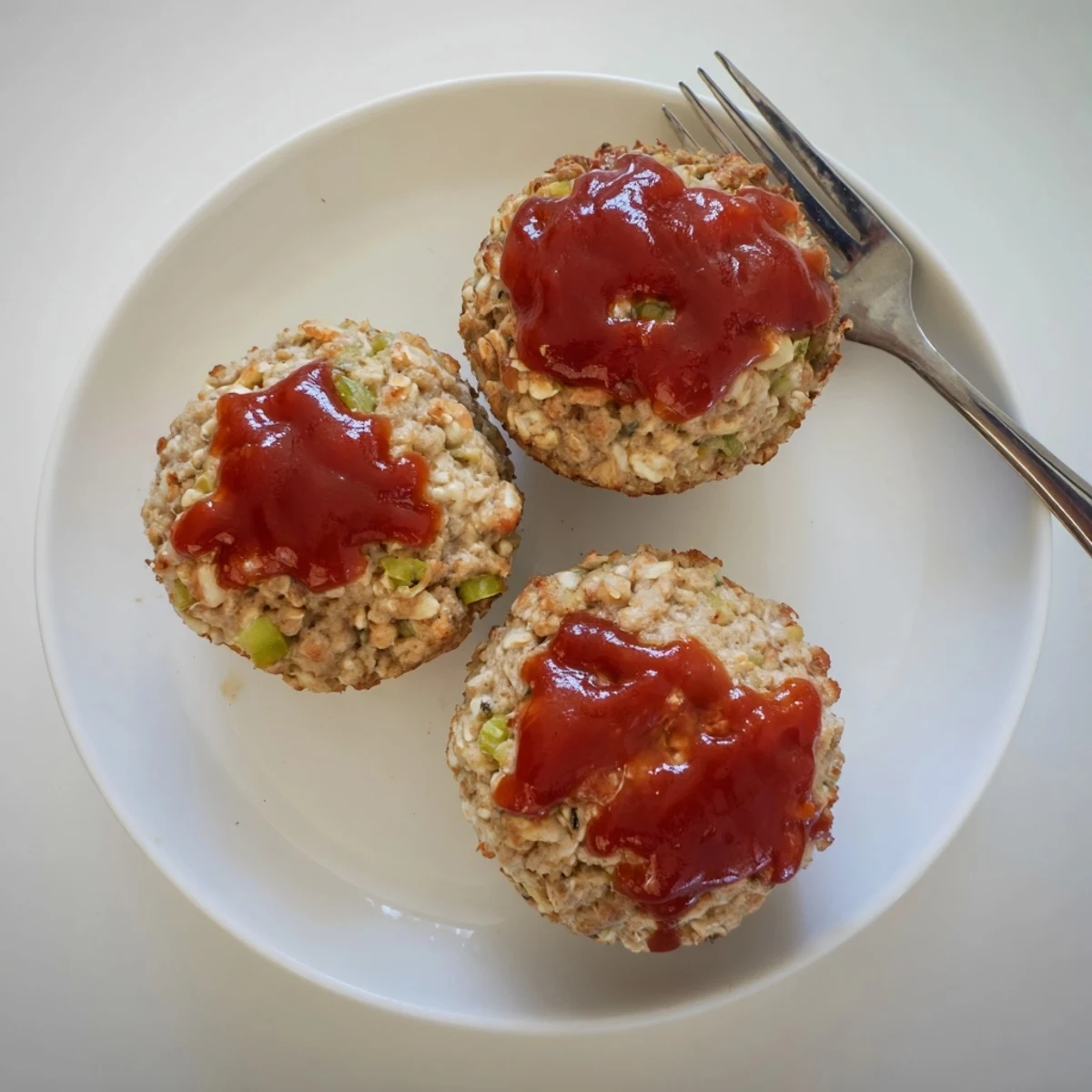 Golden glazed turkey meatloaf muffins baked in muffin tins with ketchup topping