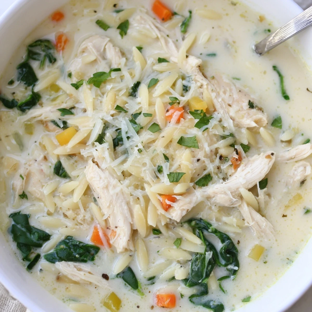 Steaming bowl of Creamy Chicken Florentine Soup With Orzo, wilted spinach.