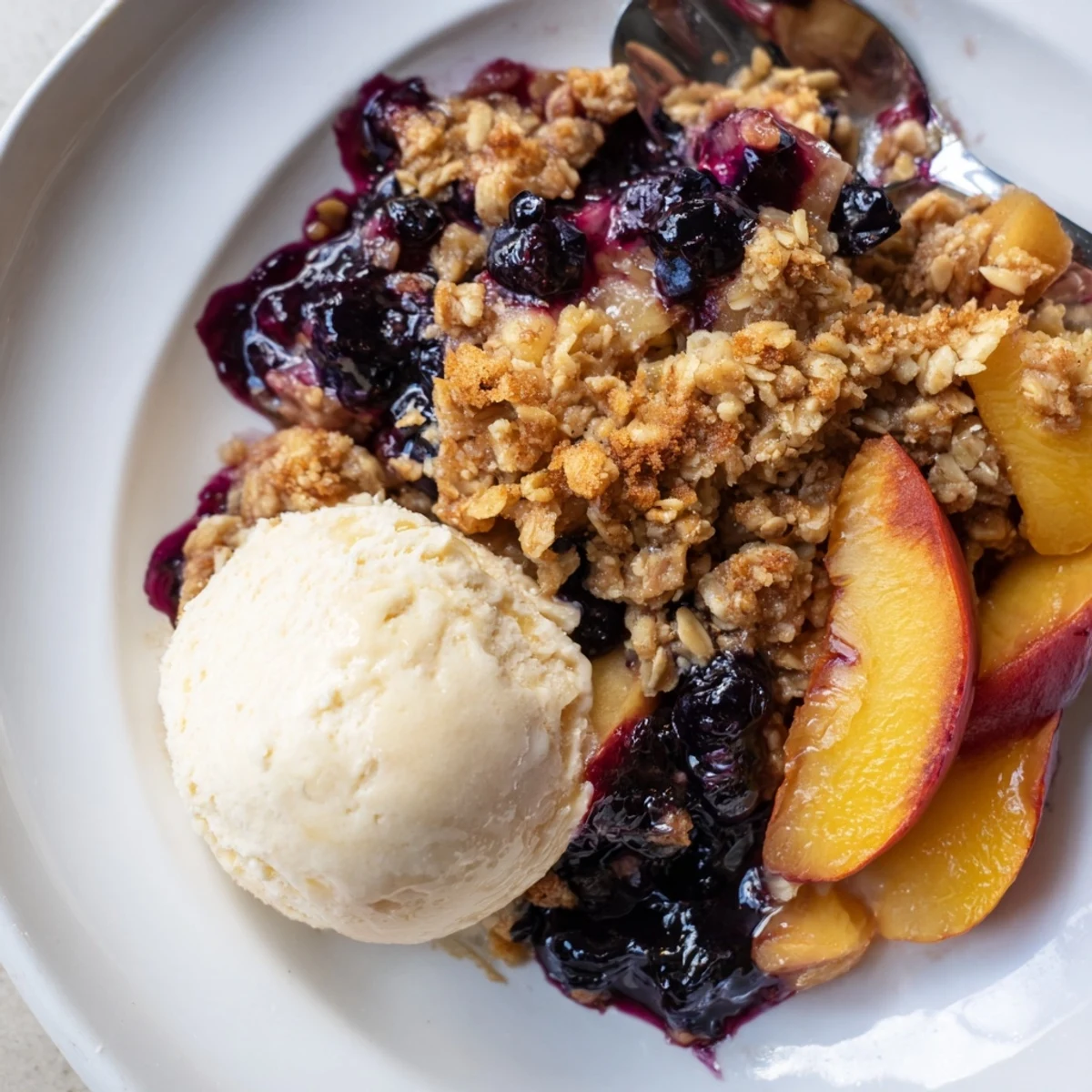 Slice of Blueberry Peach Crumble on plate, juicy fruit and crisp topping