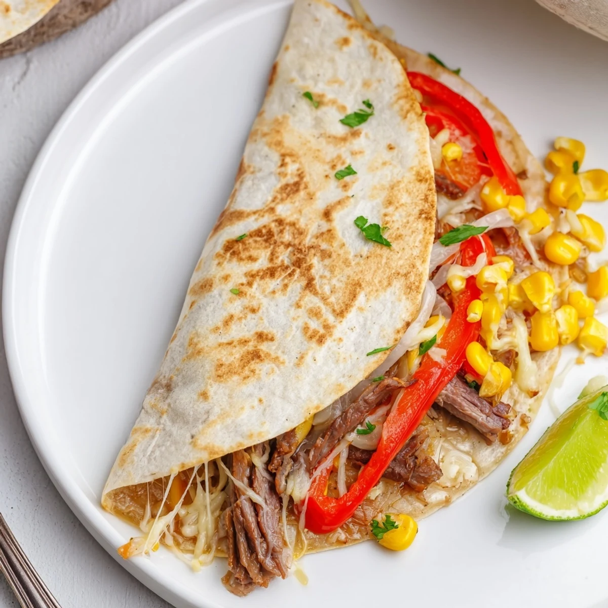 Warm Sweet Savory Beef Quesadillas Recipe sliced into wedges with sour cream.