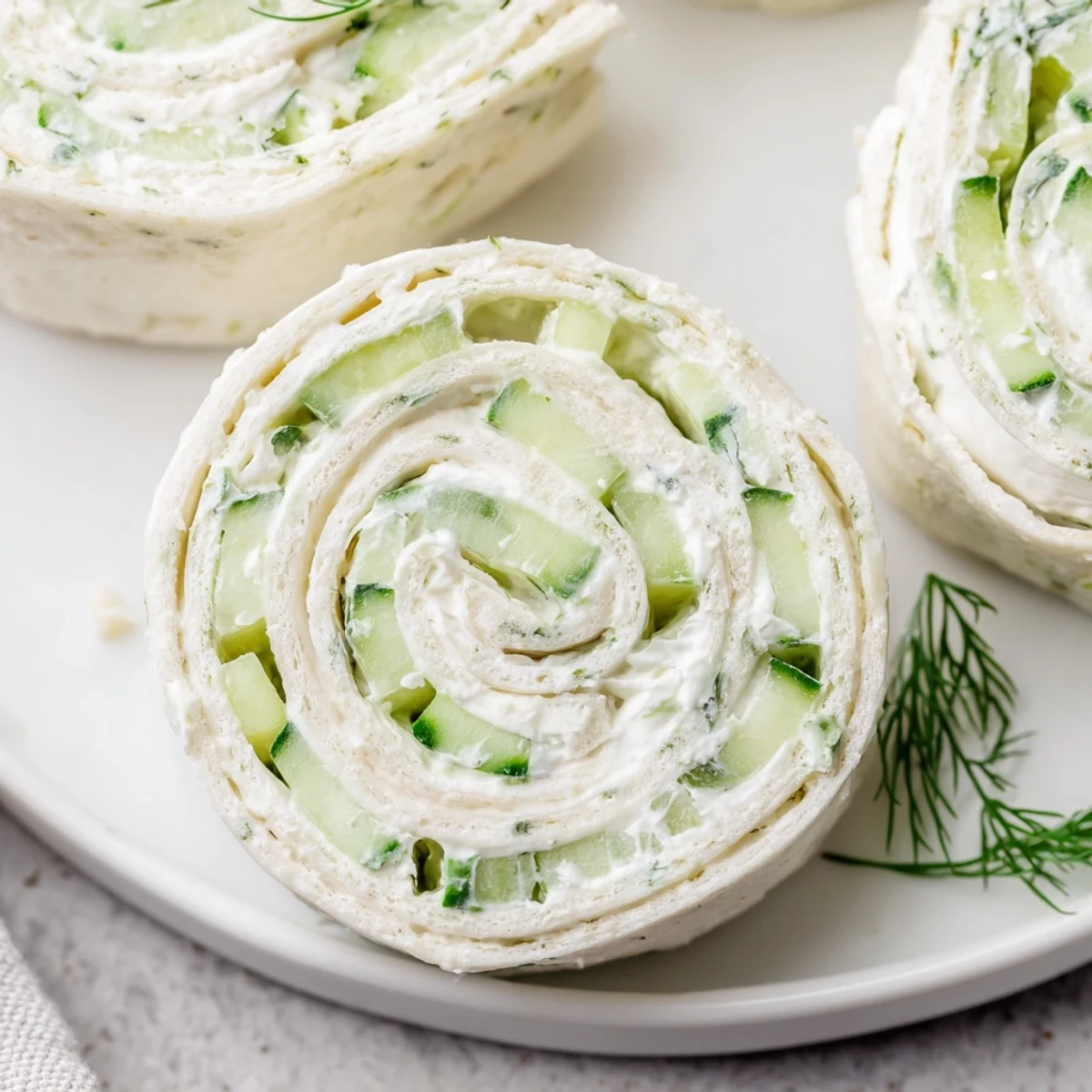 Cucumber And Dill Pinwheels arranged on platter, cream cheese swirls visible  