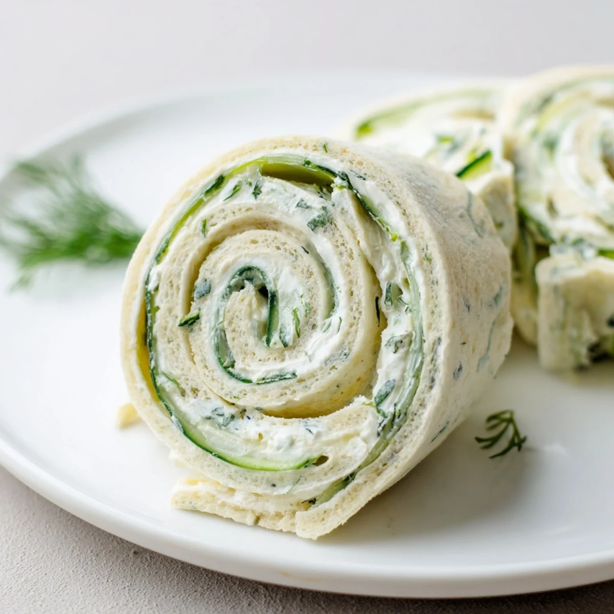 Party-ready Cucumber And Dill Pinwheels sliced into spirals, garnished with herb sprigs
