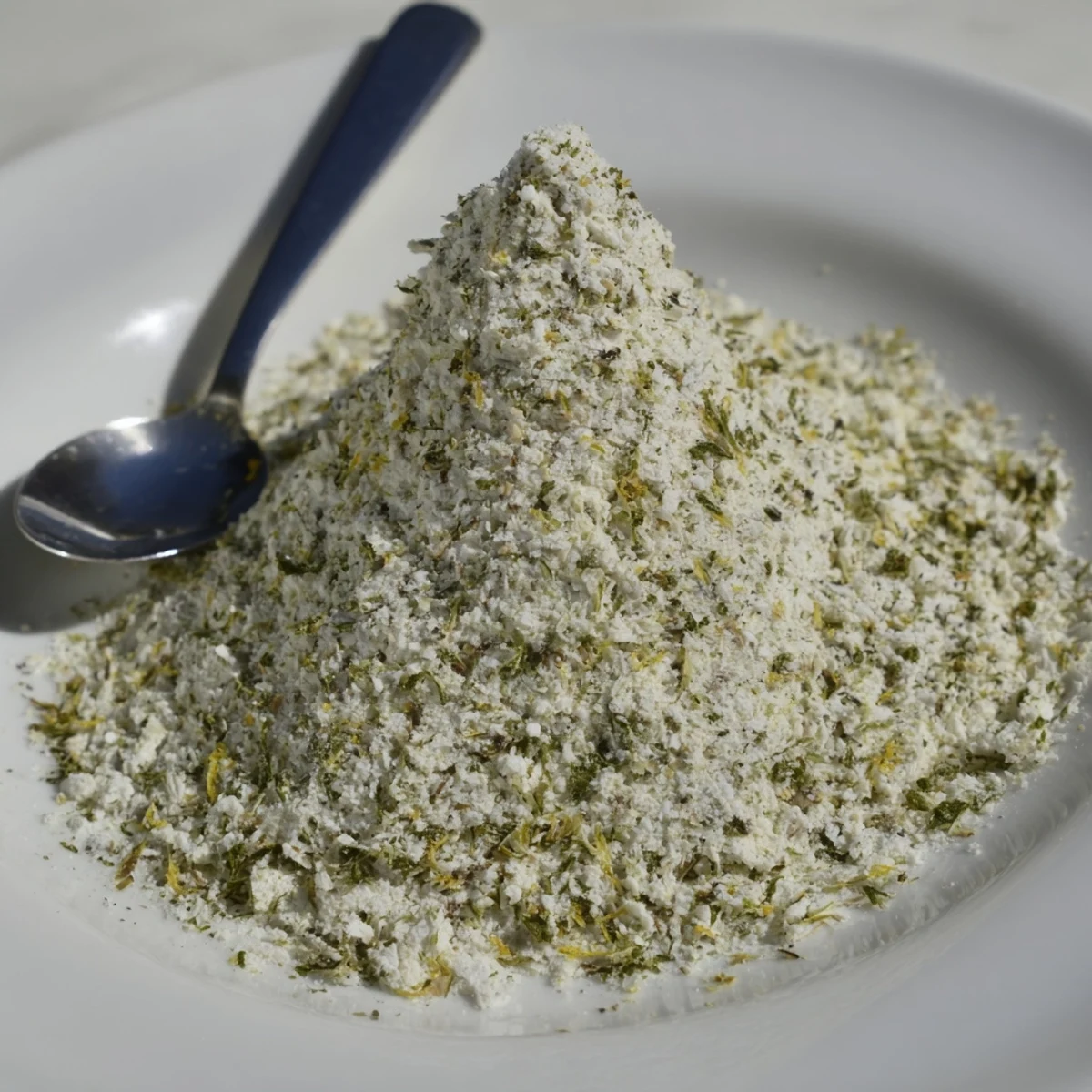 Homemade dehydrated tzatziki seasoning mix displayed in a glass jar with dried dill and parsley