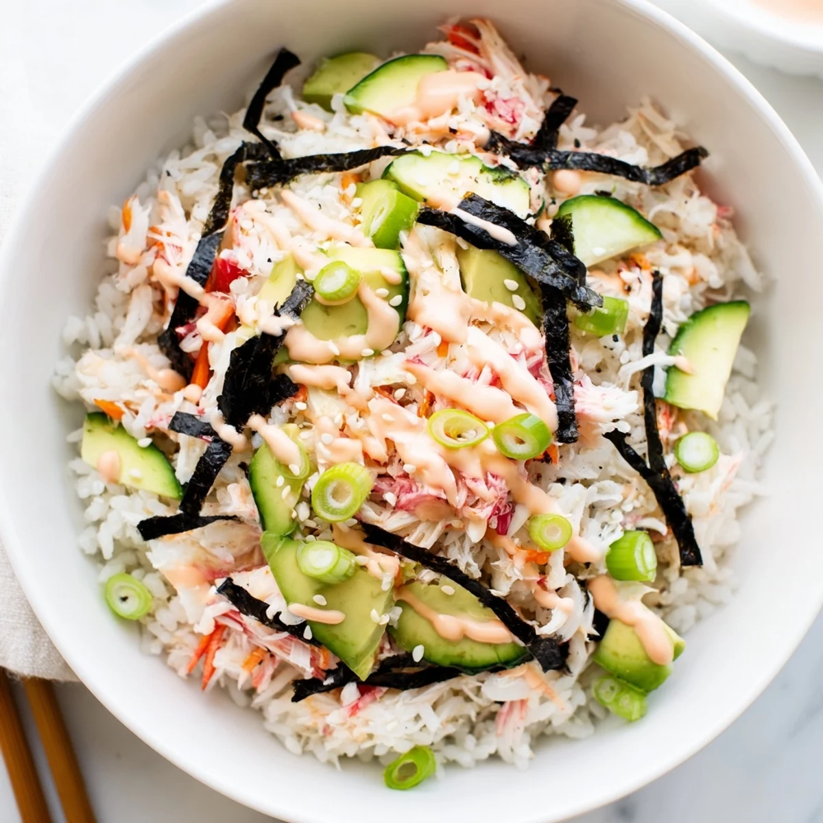 Vibrant California roll sushi bowl featuring fluffy rice topped with avocado, cucumber, shredded crab, and drizzled spicy mayo