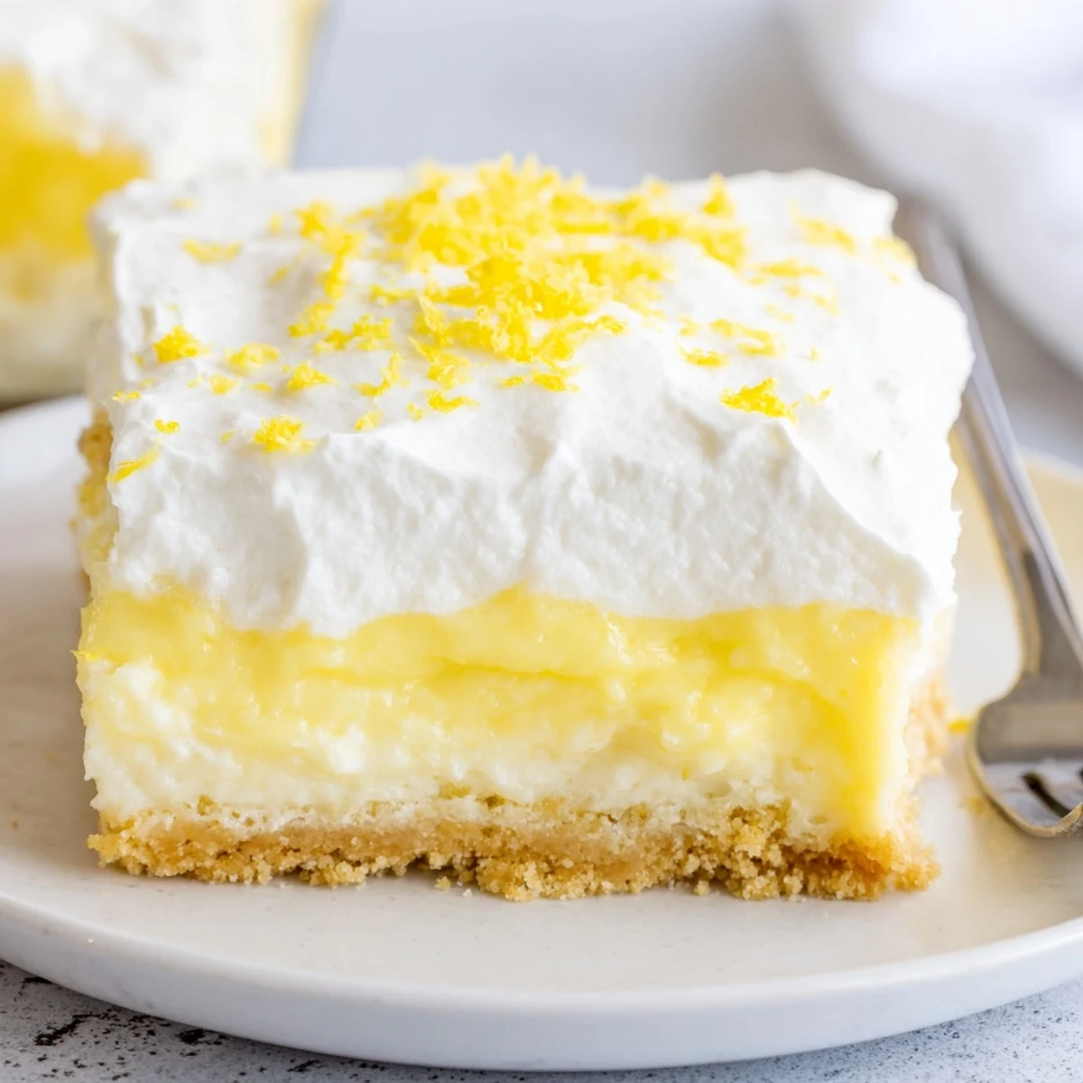 Slice of Lemon Lush Cake on plate, tangy, smooth, ready to serve