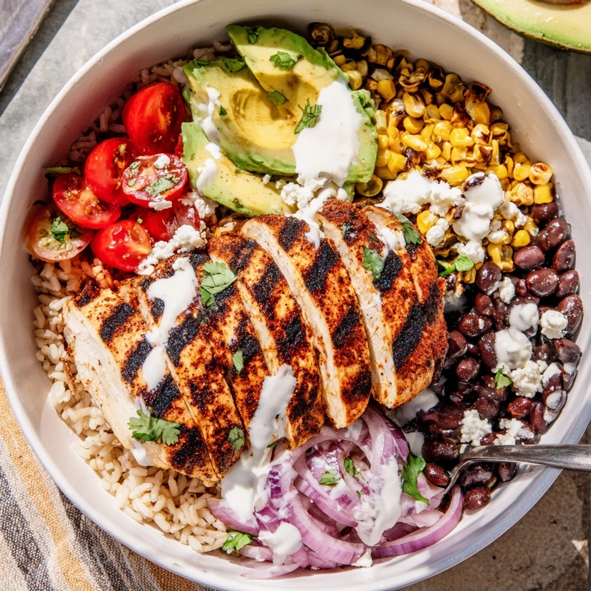 Grilled chicken slices over quinoa in a vibrant healthy street corn chicken bowl