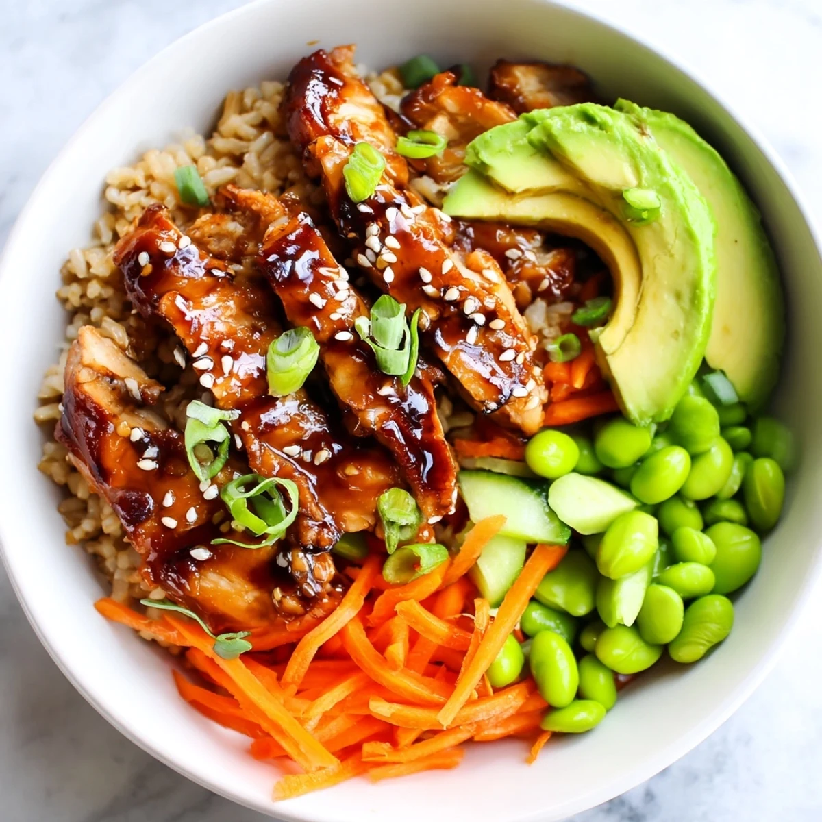 Juicy teriyaki chicken grain bowl drizzled with sauce over warm fluffy rice