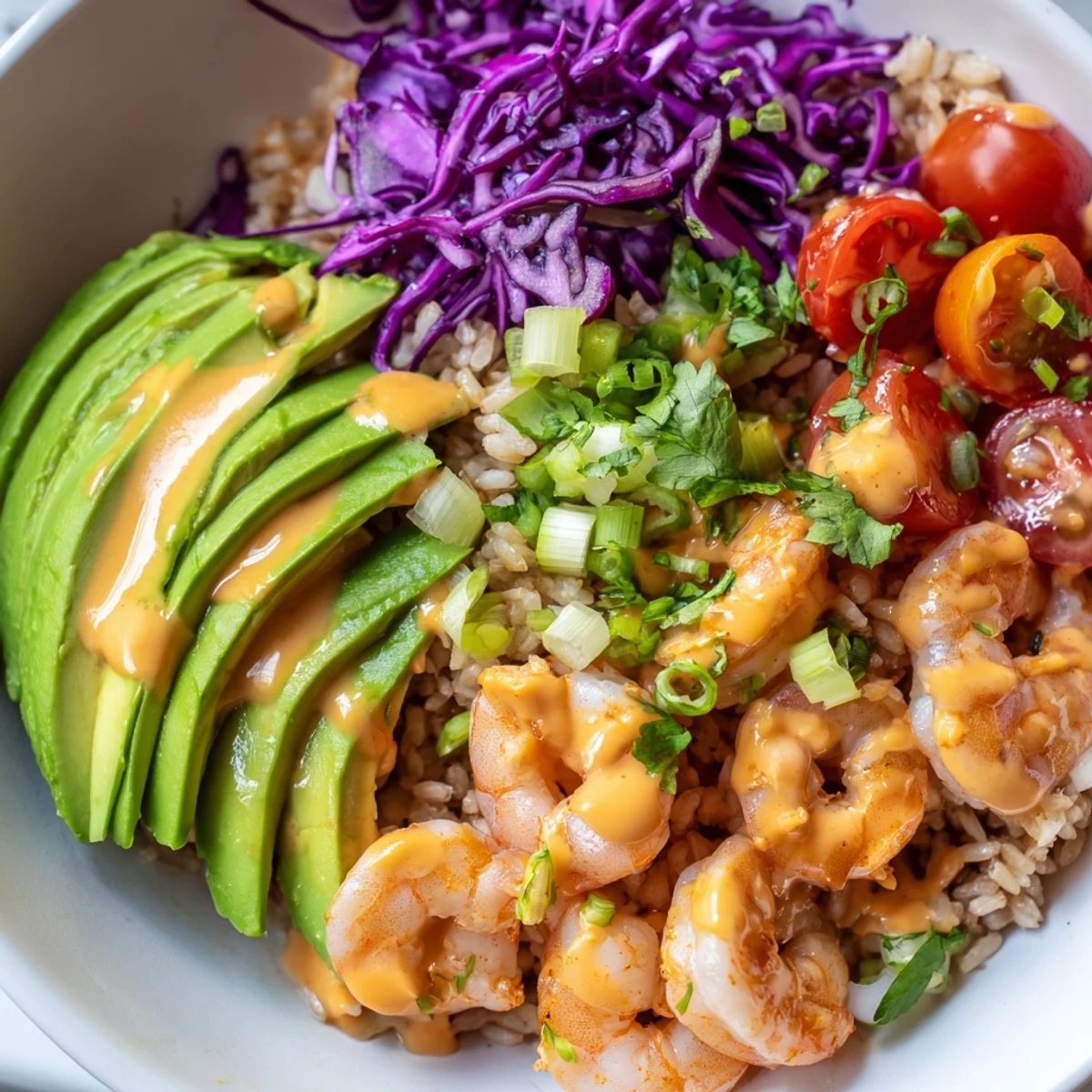 Golden shrimp grain bowl topped with fresh avocado, crisp cabbage, and zesty lime dressing