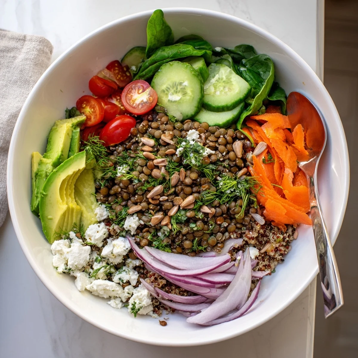 Colorful lentil grain bowl topped with fresh vegetables, avocado, and herbed dressing
