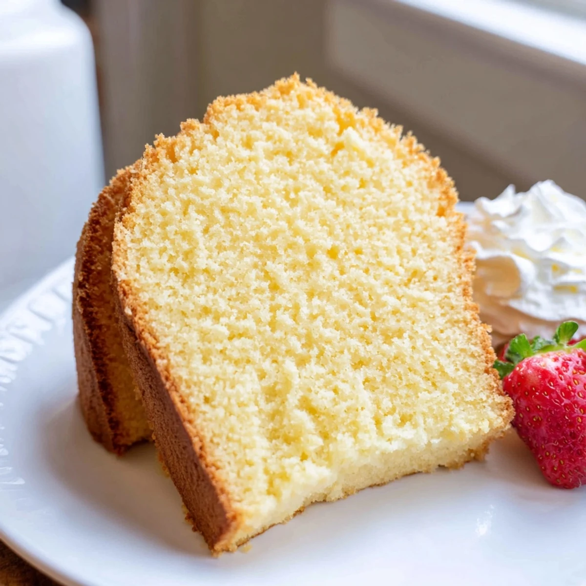 Golden pound cake slice with a tender buttery crumb served on a rustic white plate