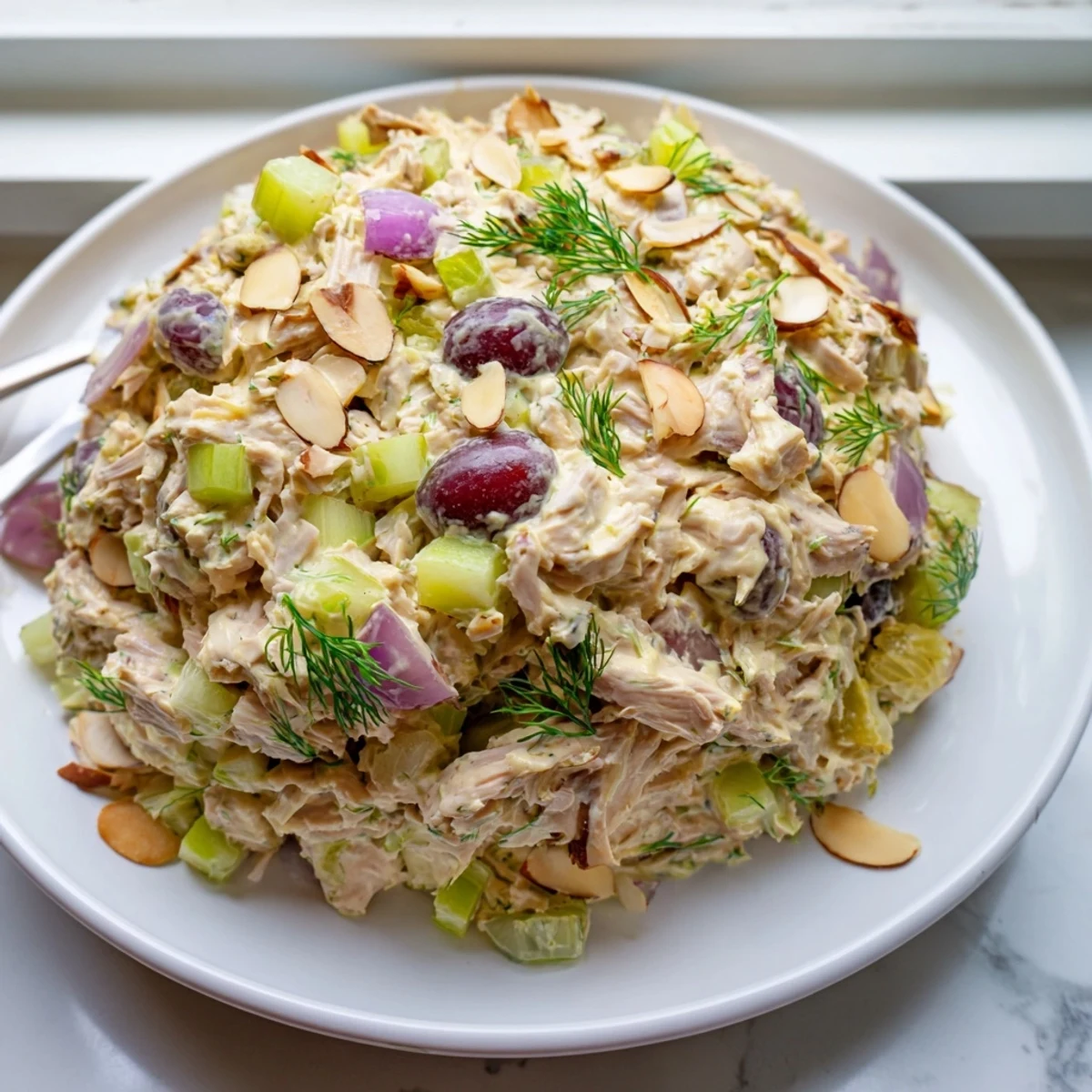 Creamy vegan chicken salad piled on toasted bread with fresh herbs and grapes