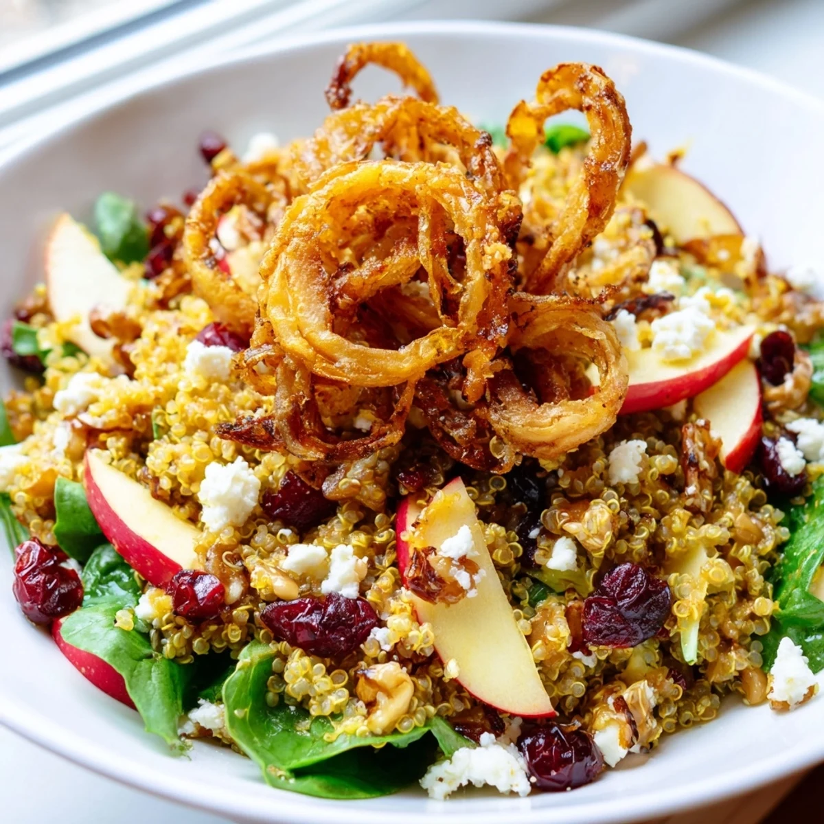 Colorful honey mustard quinoa apple salad topped with golden crispy shallots on a rustic plate