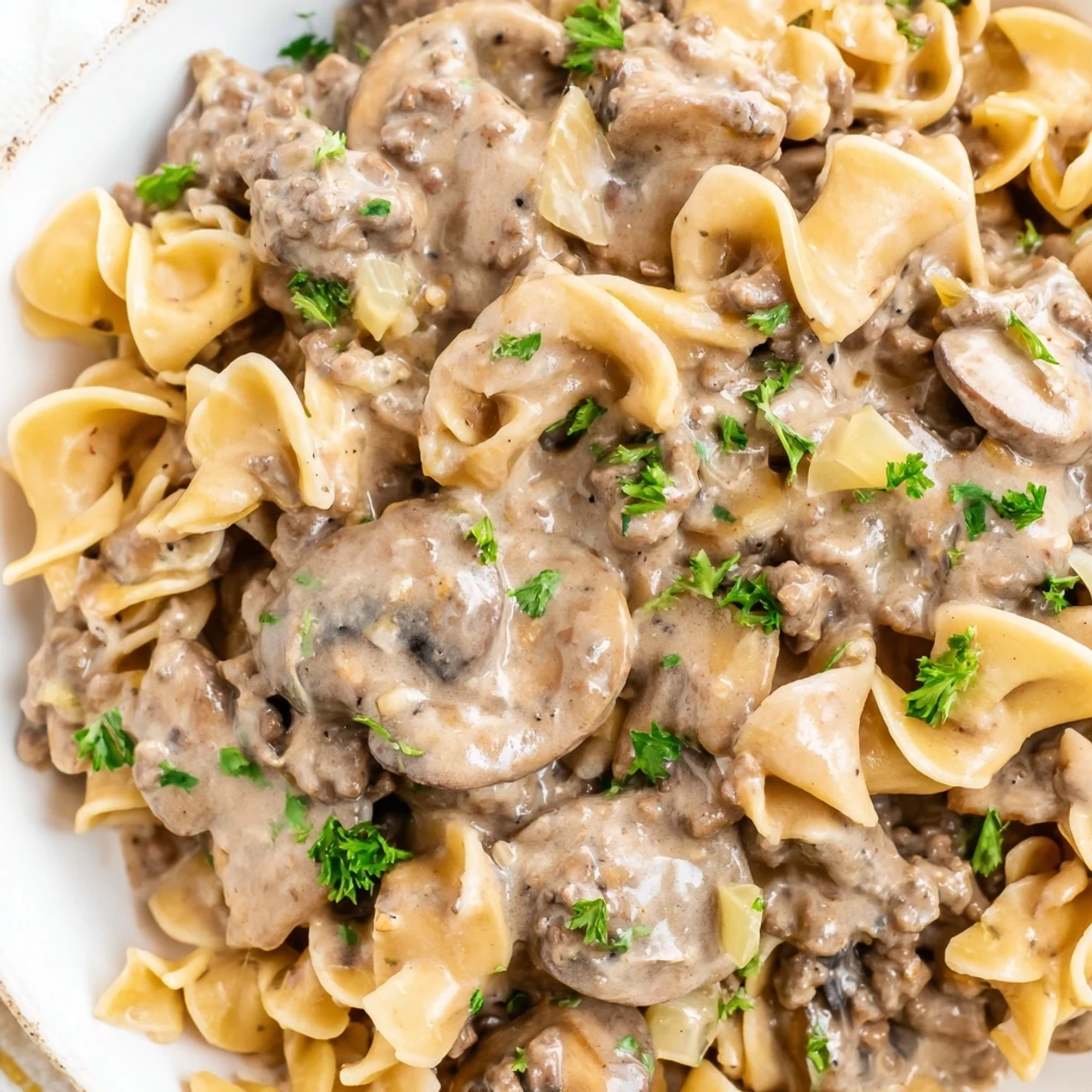 Creamy hamburger stroganoff served over tender egg noodles with fresh parsley garnish
