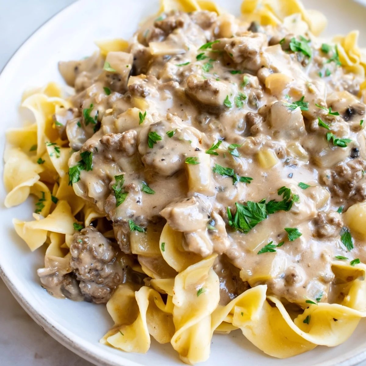 Savory hamburger stroganoff topped with chopped parsley in a warm creamy beef and mushroom sauce