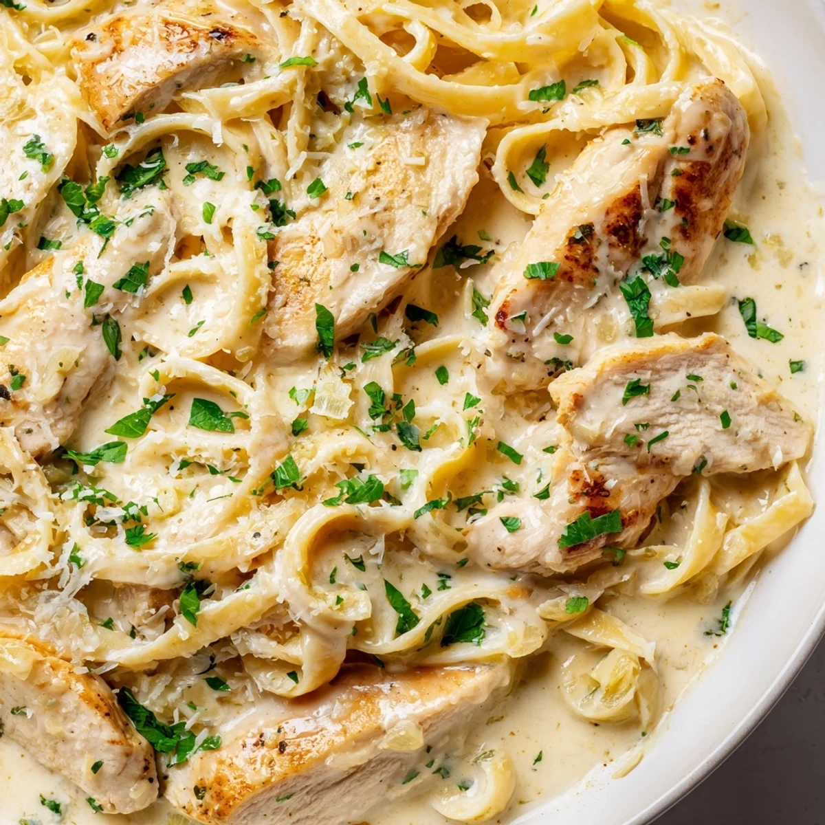 Steaming bowl of creamy garlic Parmesan chicken pasta garnished with fresh parsley