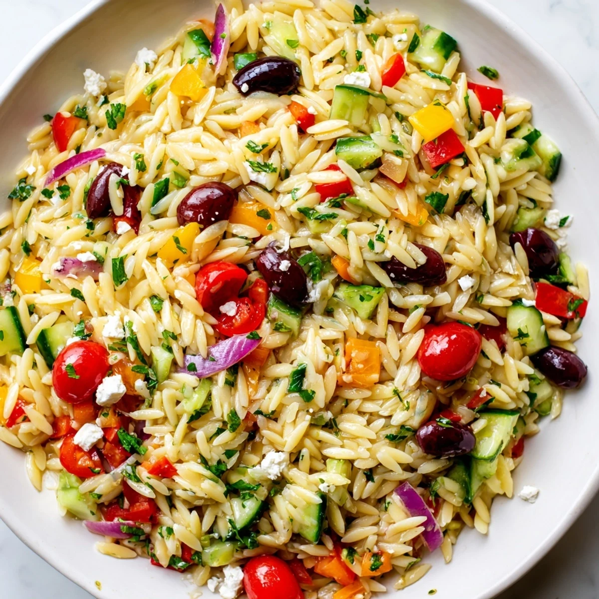 Colorful Juicy Mediterranean Orzo Pasta Salad topped with cherry tomatoes and olives