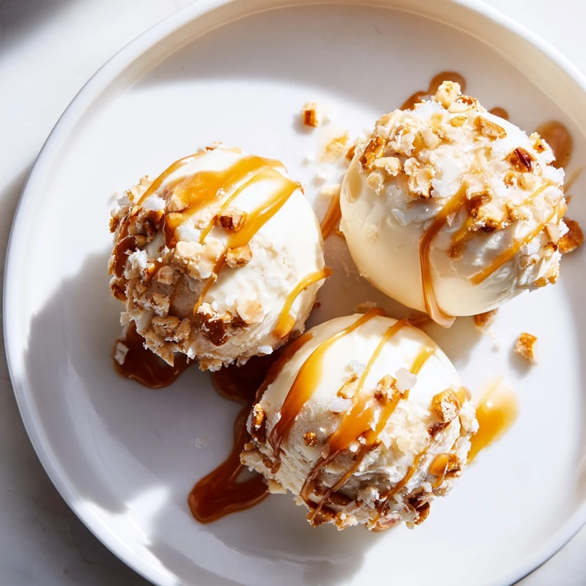 Creamy salted caramel pretzel cheesecake balls drizzled with golden caramel on a rustic tray