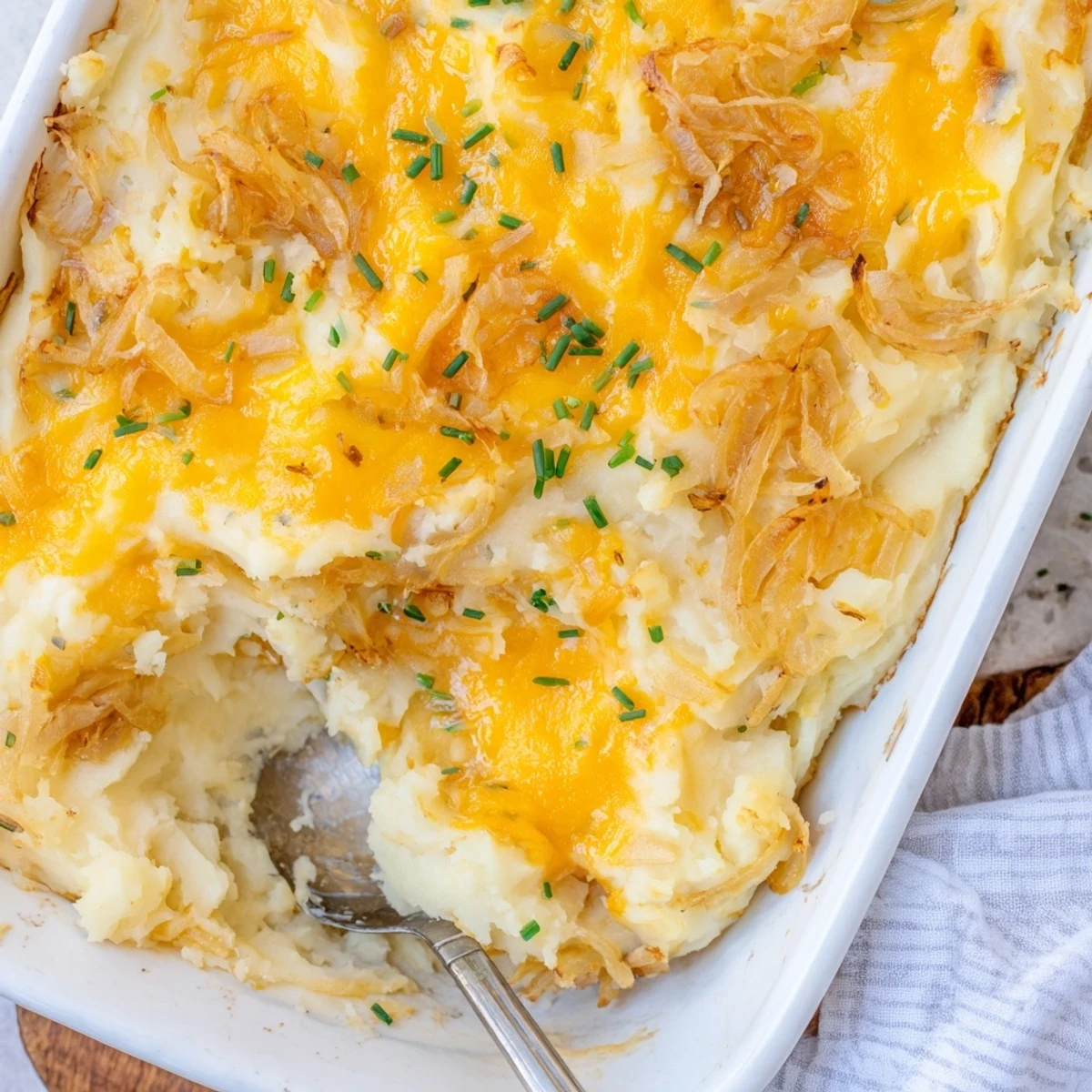 Golden bubbly cheesy onion mashed potato casserole fresh from the oven with melted cheddar topping