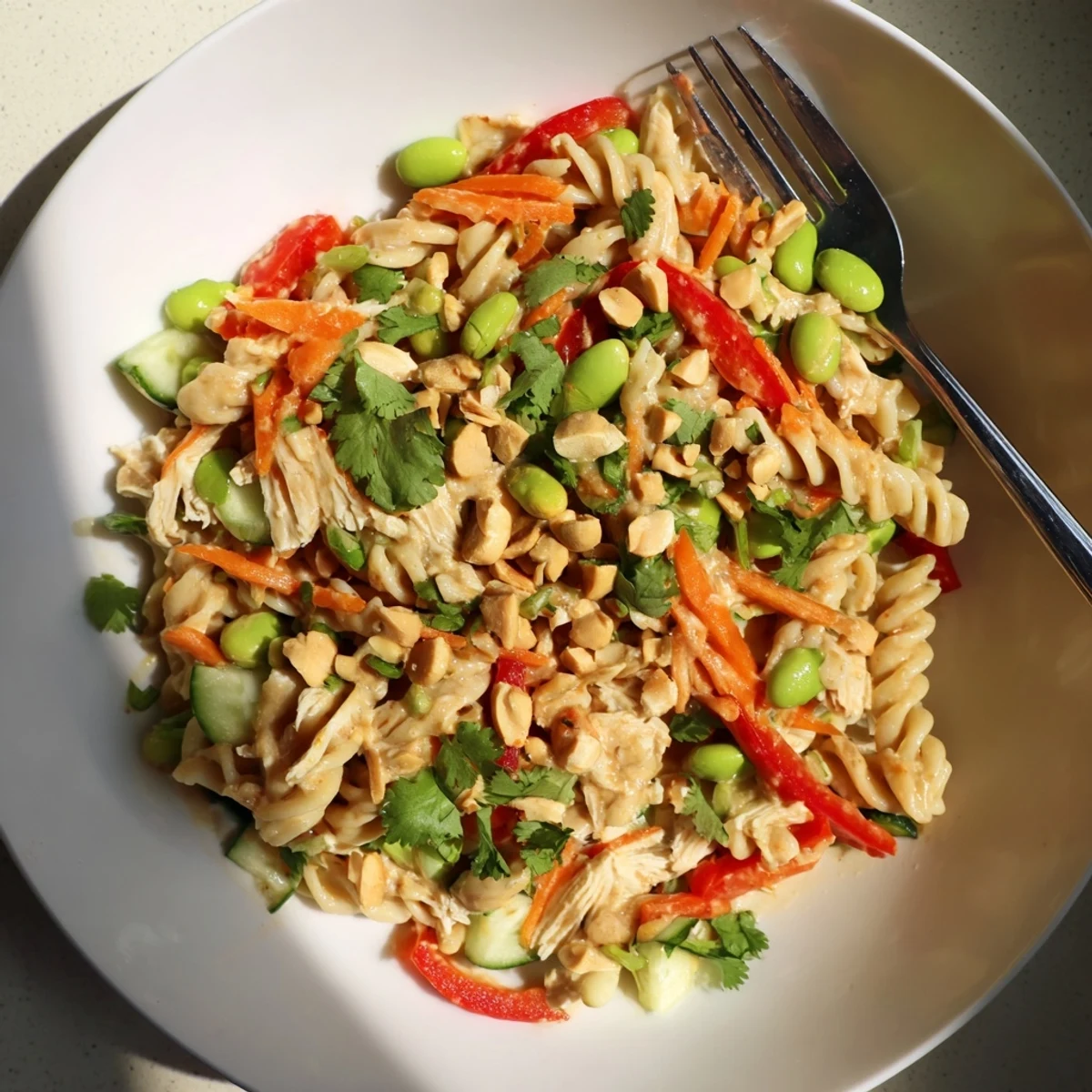 Protein Packed Thai Pasta Salad garnished with crushed peanuts and lime wedges on a platter
