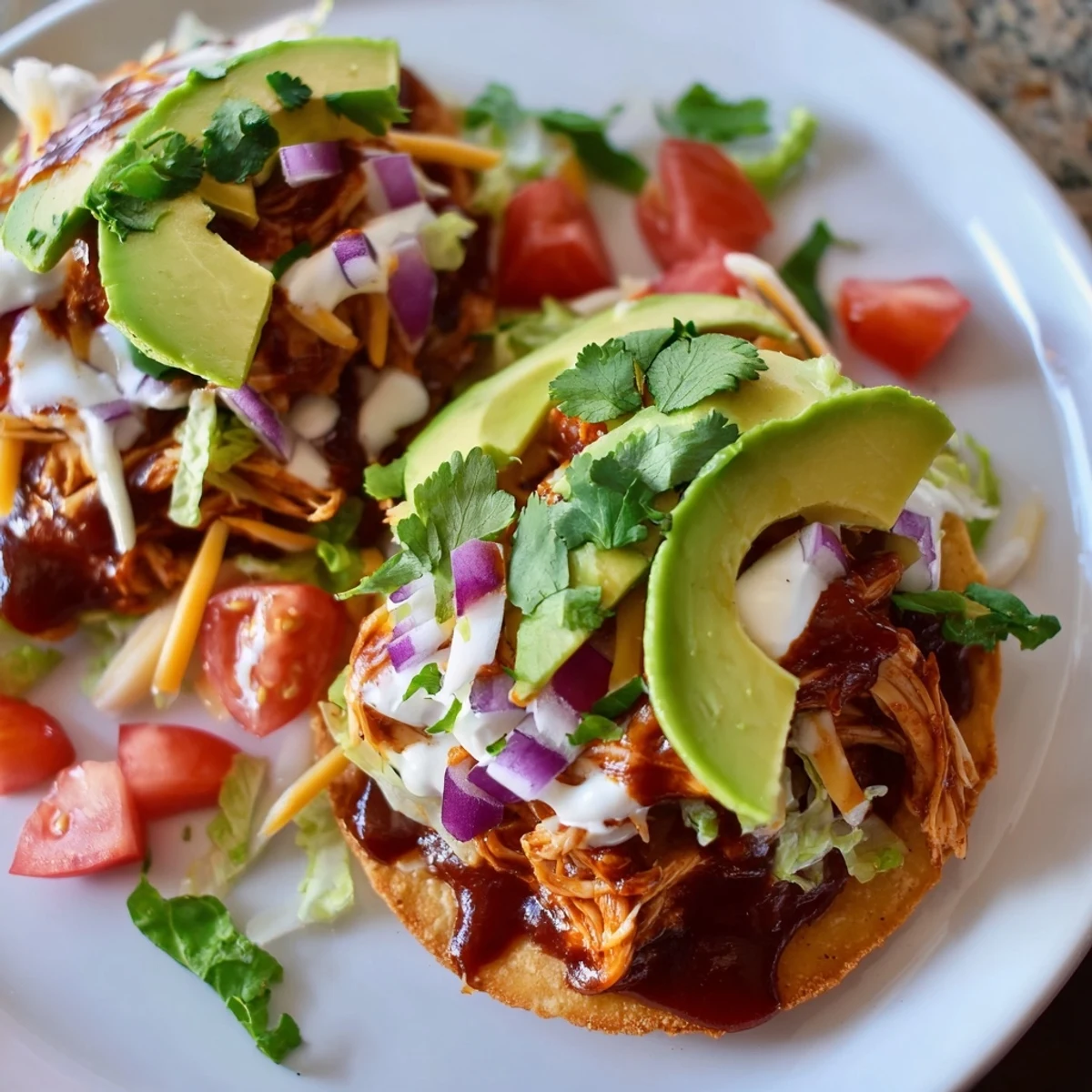 Golden corn shells loaded with tender sweet smoky BBQ chicken tostadas drizzled in cool sour cream