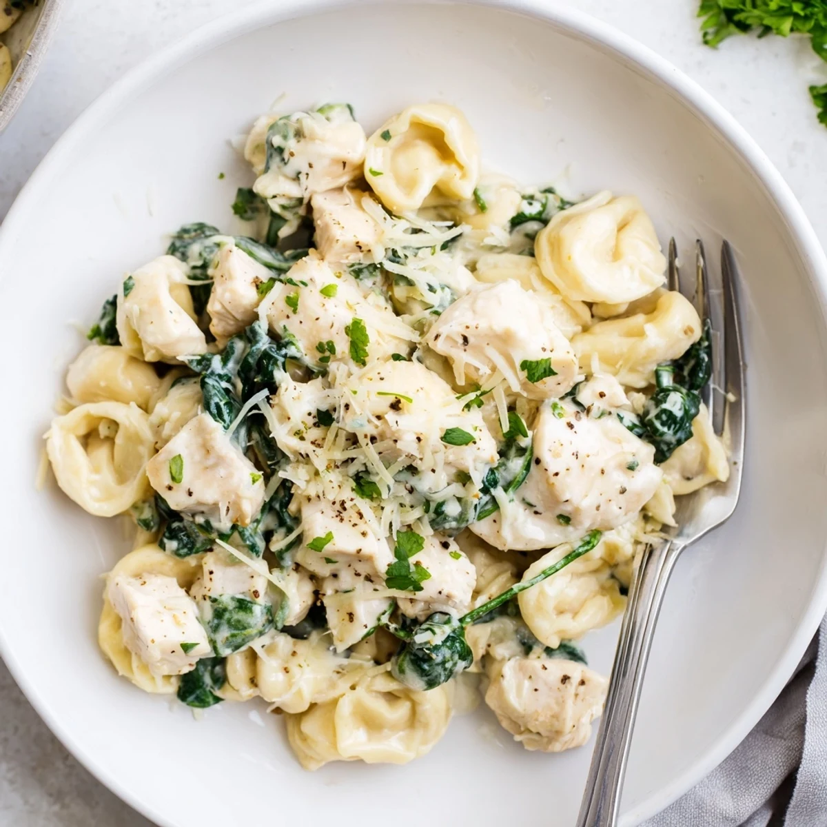 Creamy garlic chicken tortellini with spinach in a golden parmesan sauce steaming in a cast iron skillet