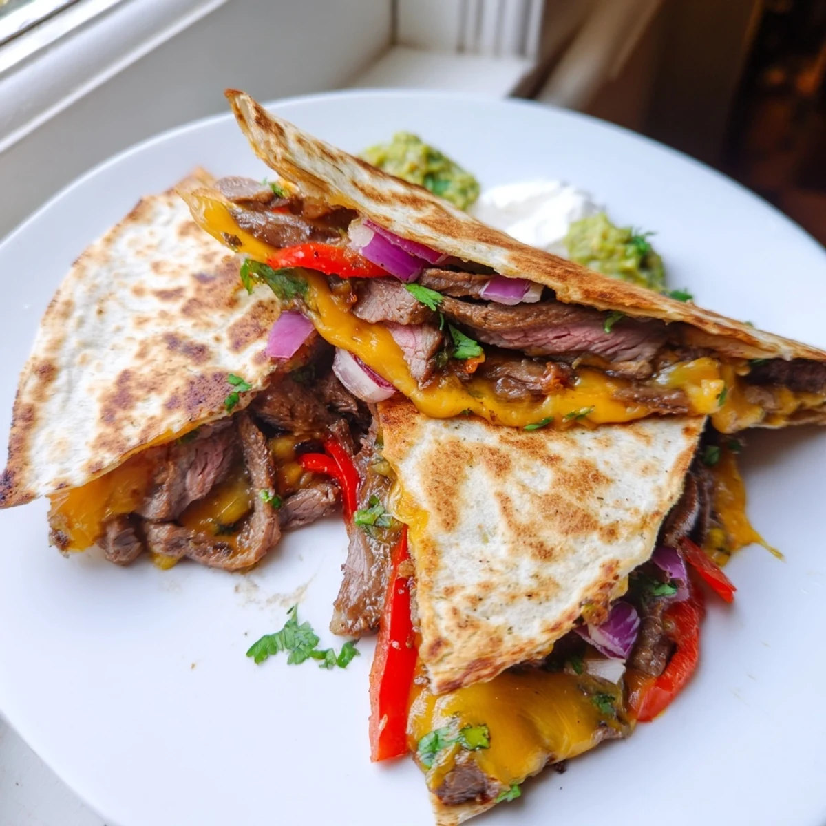 Steak quesadillas cut into triangles oozing with melted cheese beside fresh salsa and guacamole
