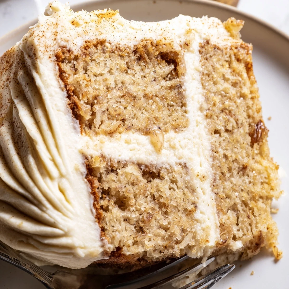 Brown Butter Banana Cake sliced thick with swirls of creamy frosting