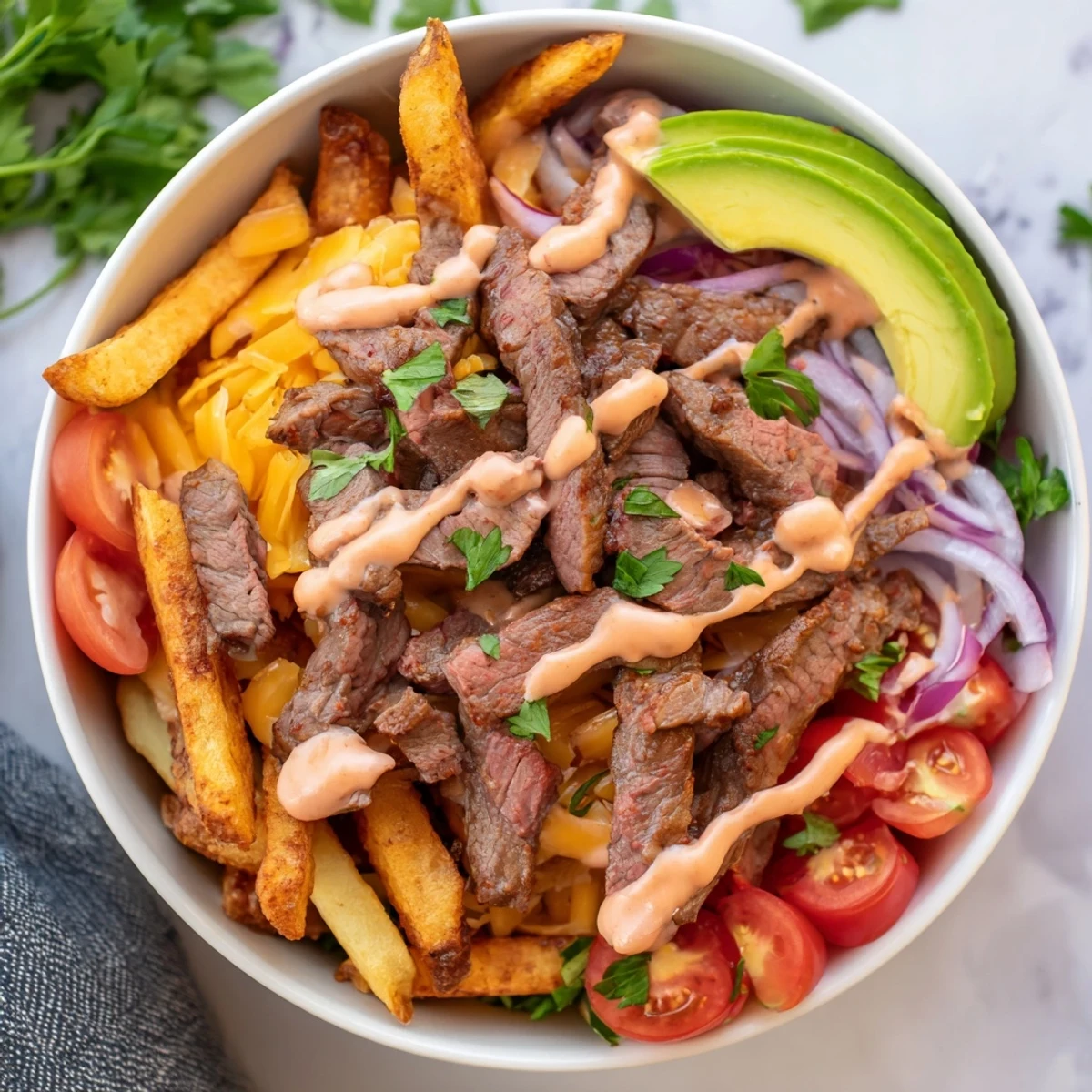Crispy golden fries topped with sizzling steak strips and creamy avocado in a rustic bowl