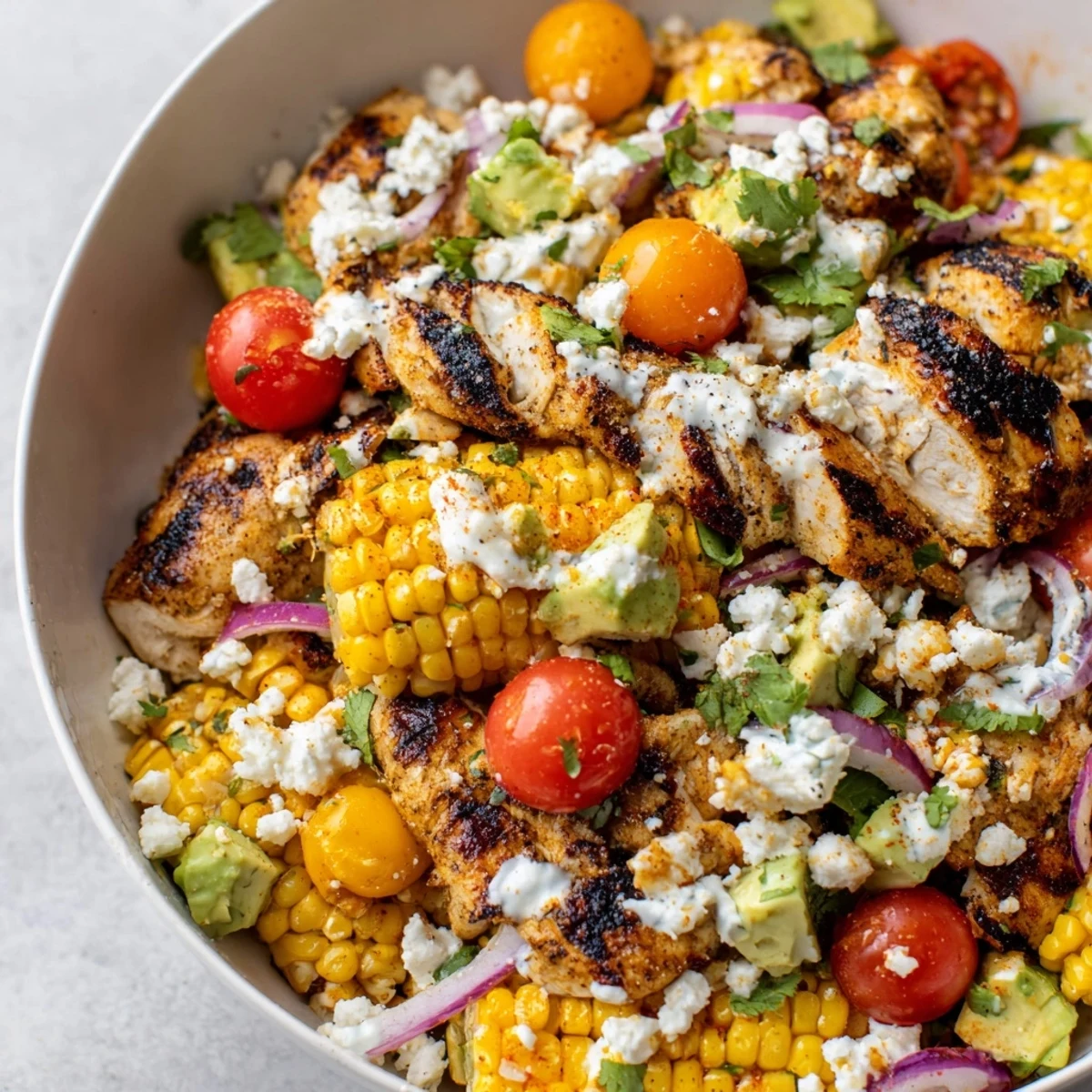 High Protein Chicken Street Corn Salad topped with sliced grilled chicken and crumbled cotija cheese
