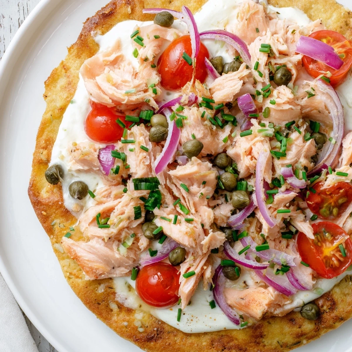 Golden crispy tortilla pizza topped with flaked salmon, melted mozzarella, and fresh red onion slices  