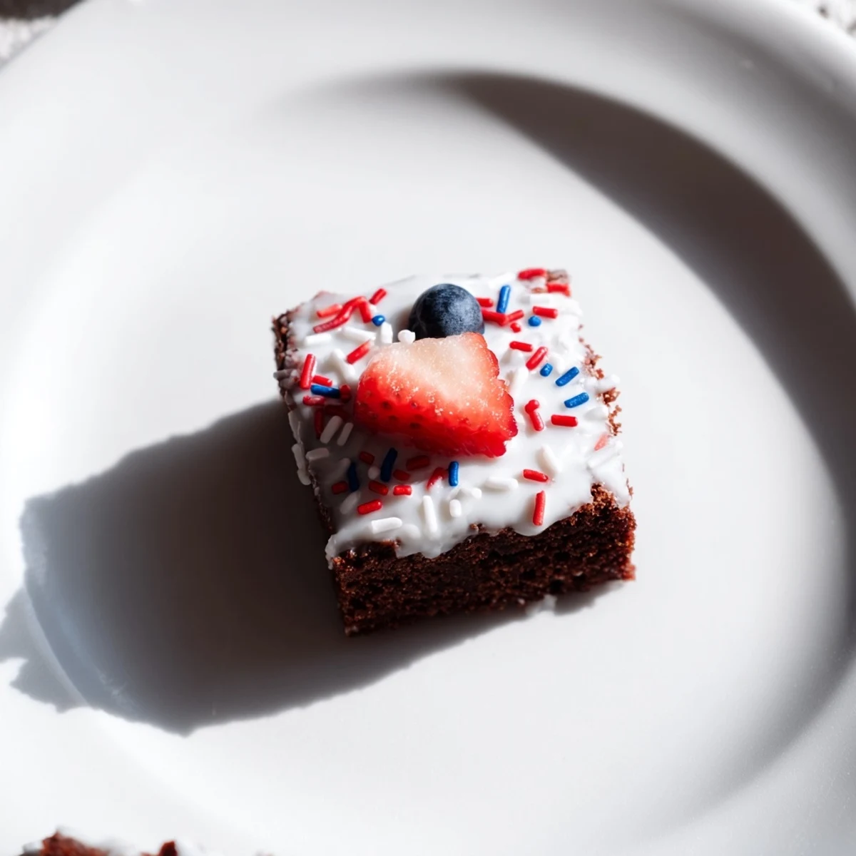 Chocolatey Fourth of July Brownie Bites arranged on a platter with fresh berries and stars.