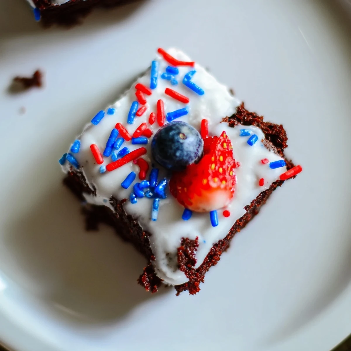 Bite-sized brownies glazed with white icing and colorful sprinkles, perfect for Independence Day celebrations.