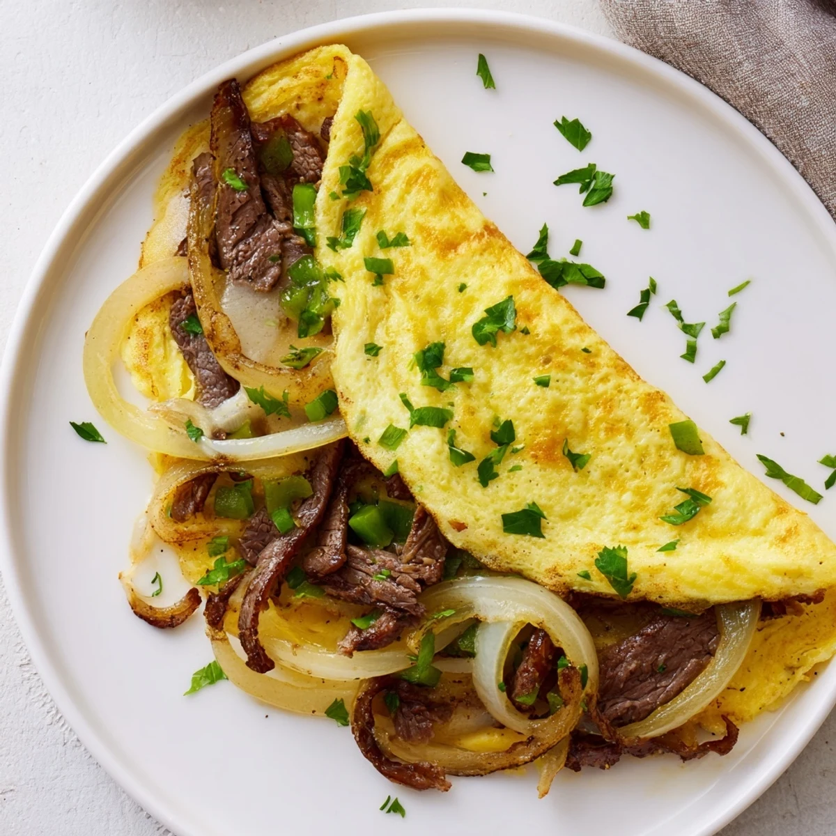 Golden Philly cheesesteak omelette filled with tender steak, peppers, and melted provolone cheese.  