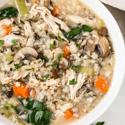 Creamy Instant Pot Chicken and Wild Rice Soup in a rustic mug with carrots, celery, and wild rice.