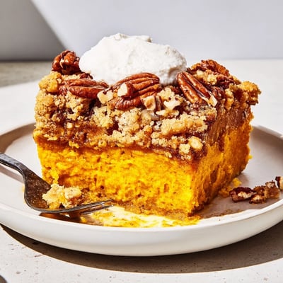 Creamy spiced Pumpkin Dump Cake scooped into a bowl with vanilla ice cream
