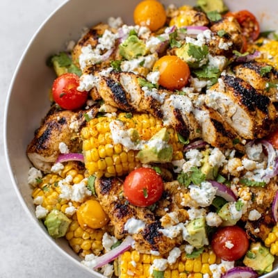 High Protein Chicken Street Corn Salad topped with sliced grilled chicken and crumbled cotija cheese
